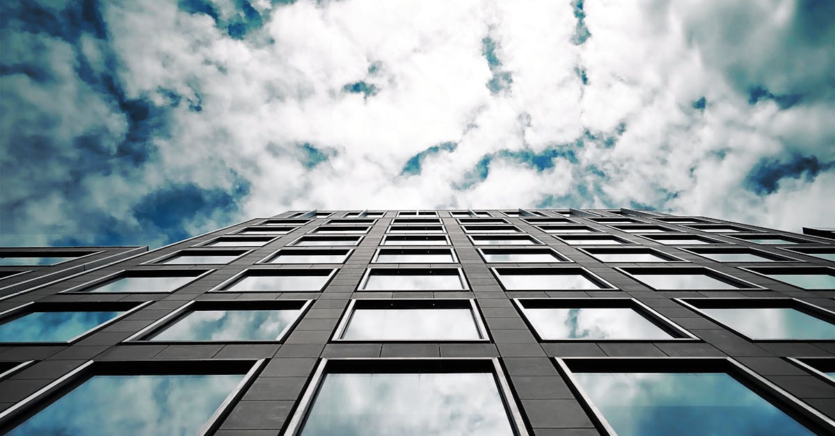 Low angle of a modern skyscraper reflecting clouds in its glass windows with a dramatic sky.